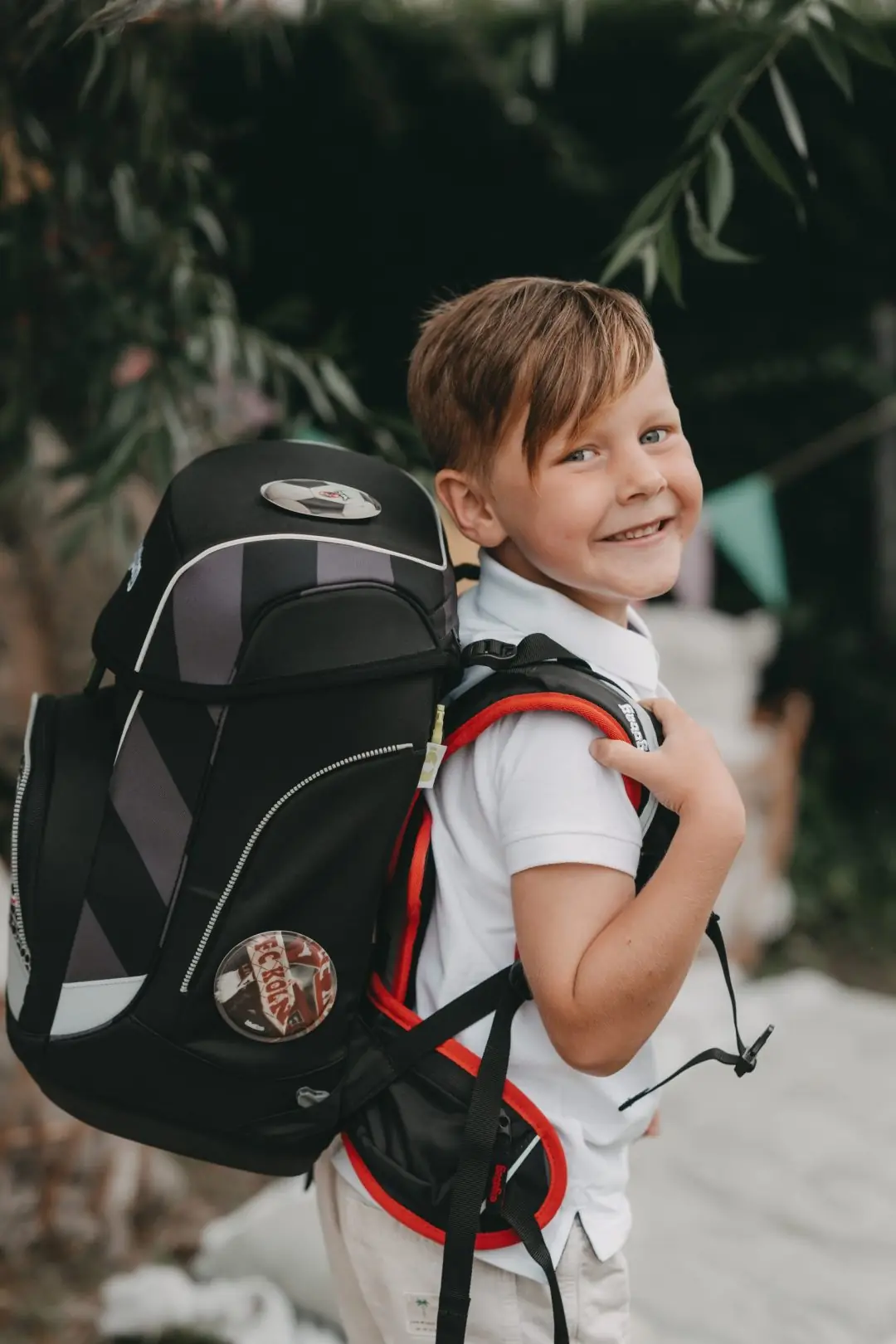 Junge mit Schulranzen lächelt über die Schulter