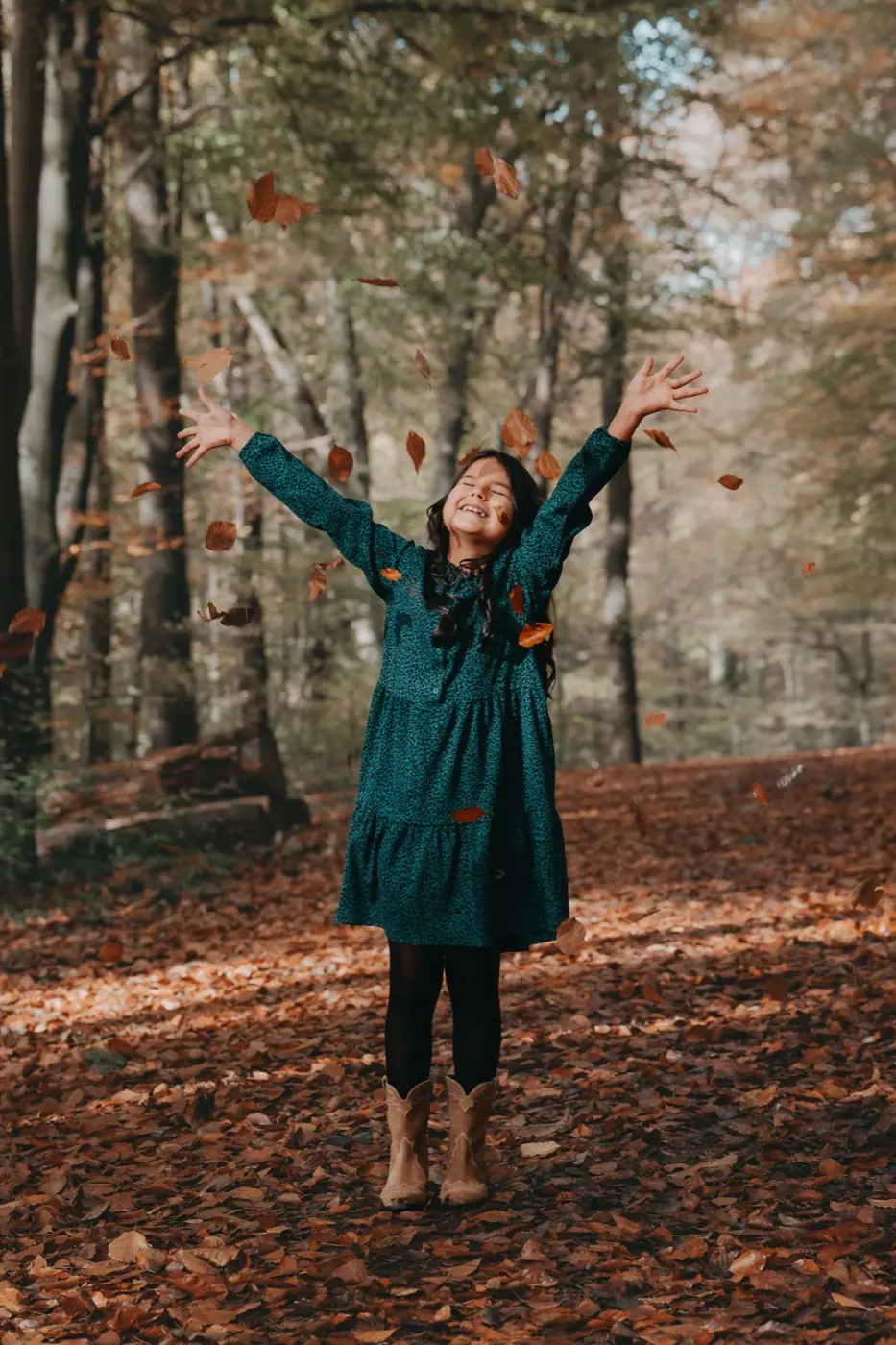 Mädchen wirft im Herbstwald Laub in die Luft