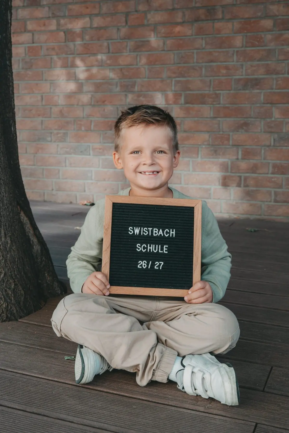 Junge mit Schild „Swistbachschule 26/27“