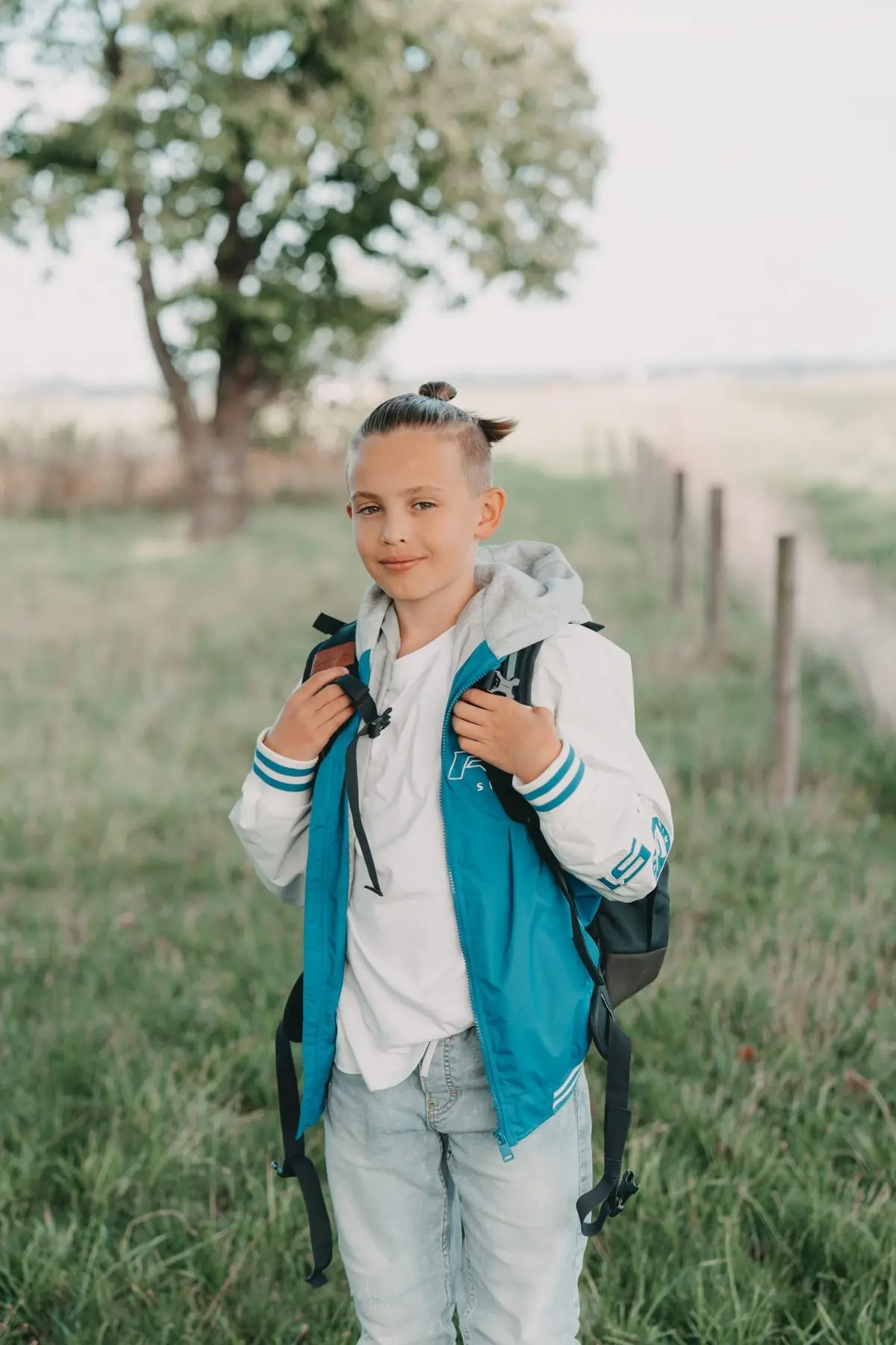 Junge mit Schulranzen auf einer Wiese